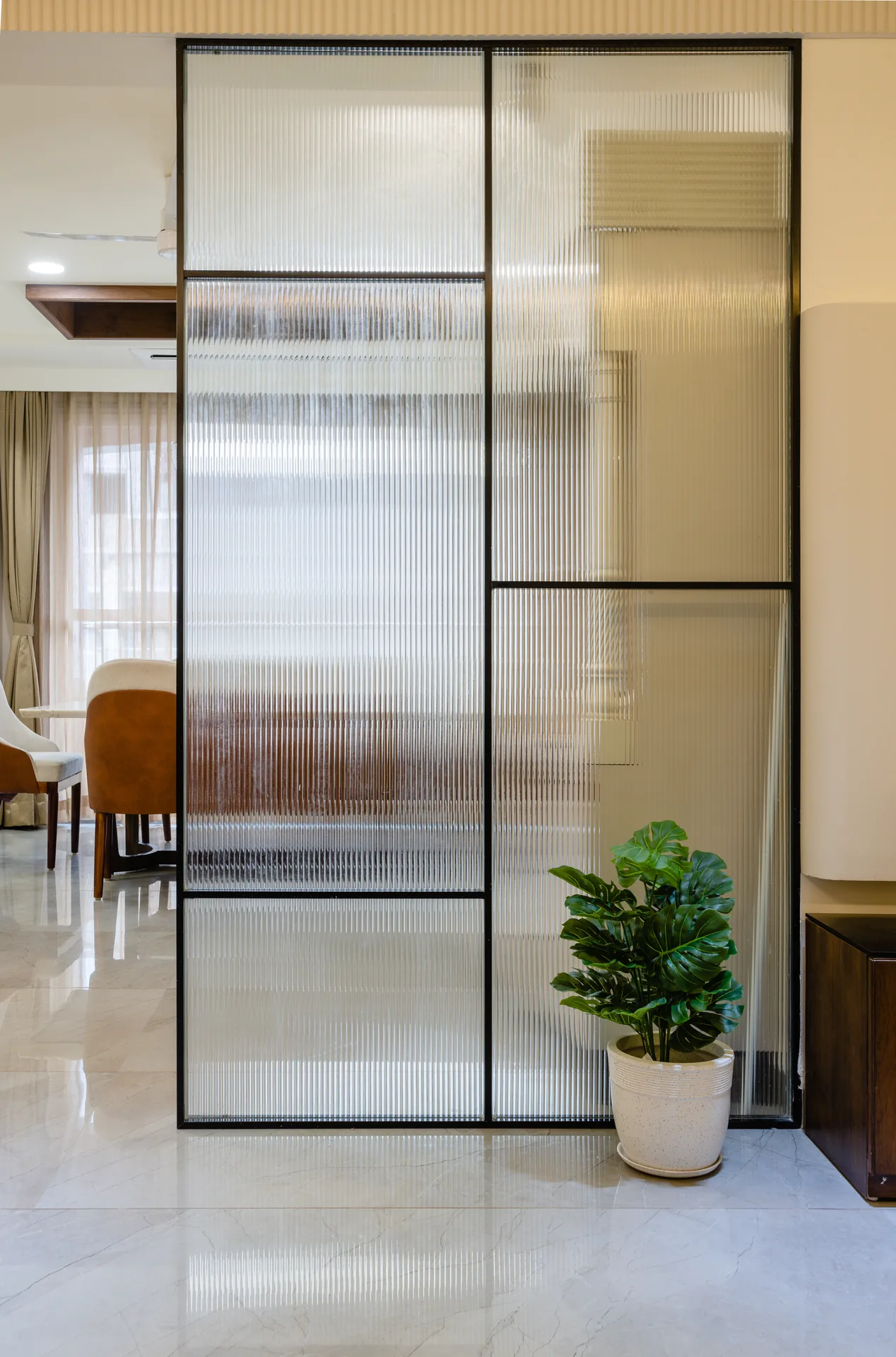A refined kitchen and dining space featuring sleek cabinetry, subtle glass partitions, warm lighting, and elegant finishes, creating a seamless balance of functionality and contemporary living.