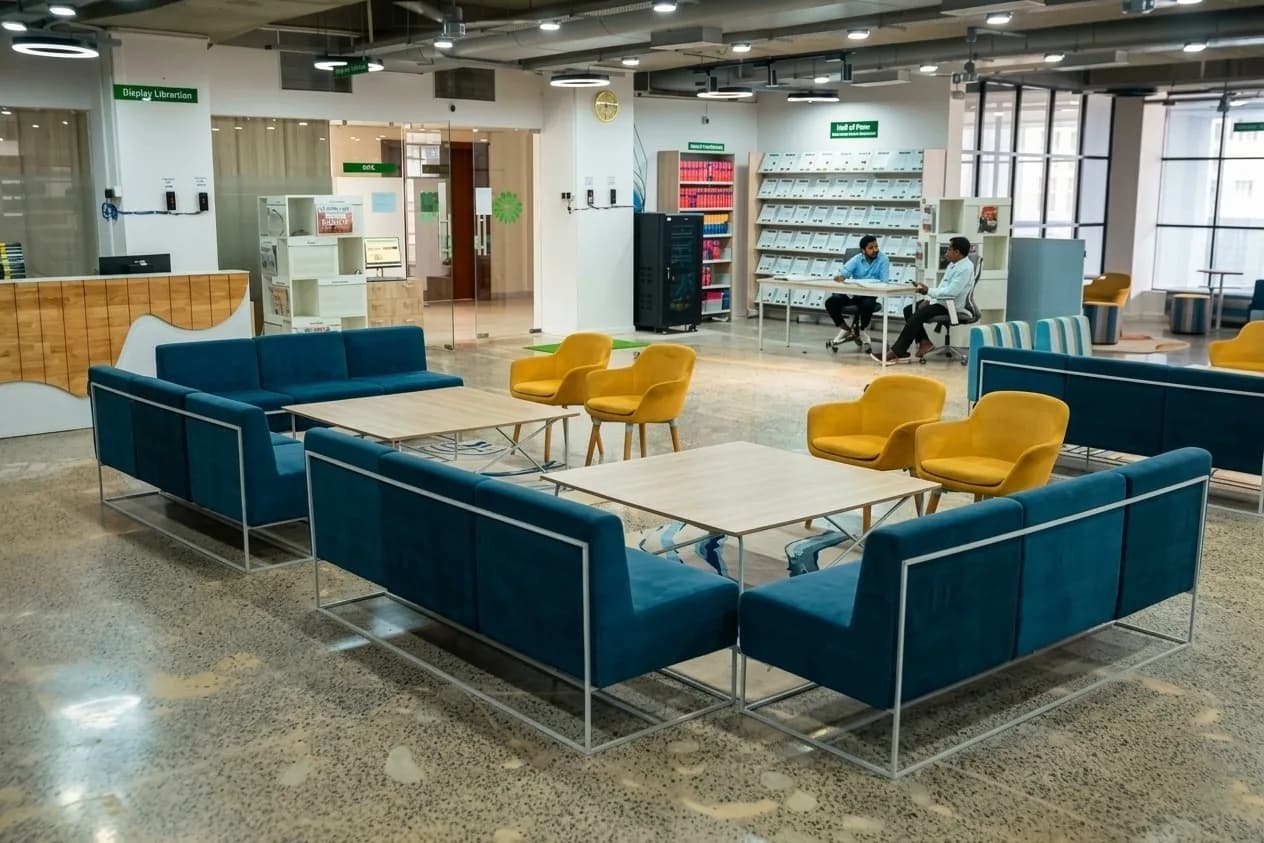 A vibrant library lounge featuring comfortable seating, bold color accents, open layouts, and flexible gathering spaces, creating an inviting setting for reading, interaction, and relaxation.