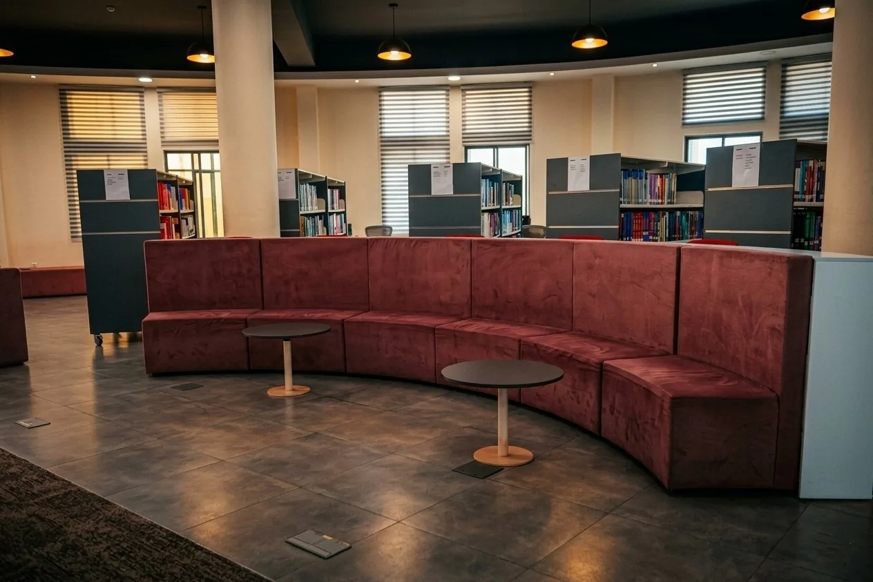 A well-organized library floor featuring extensive book shelving, comfortable curved seating, and dedicated reading zones, creating a calm and accessible environment for focused study.