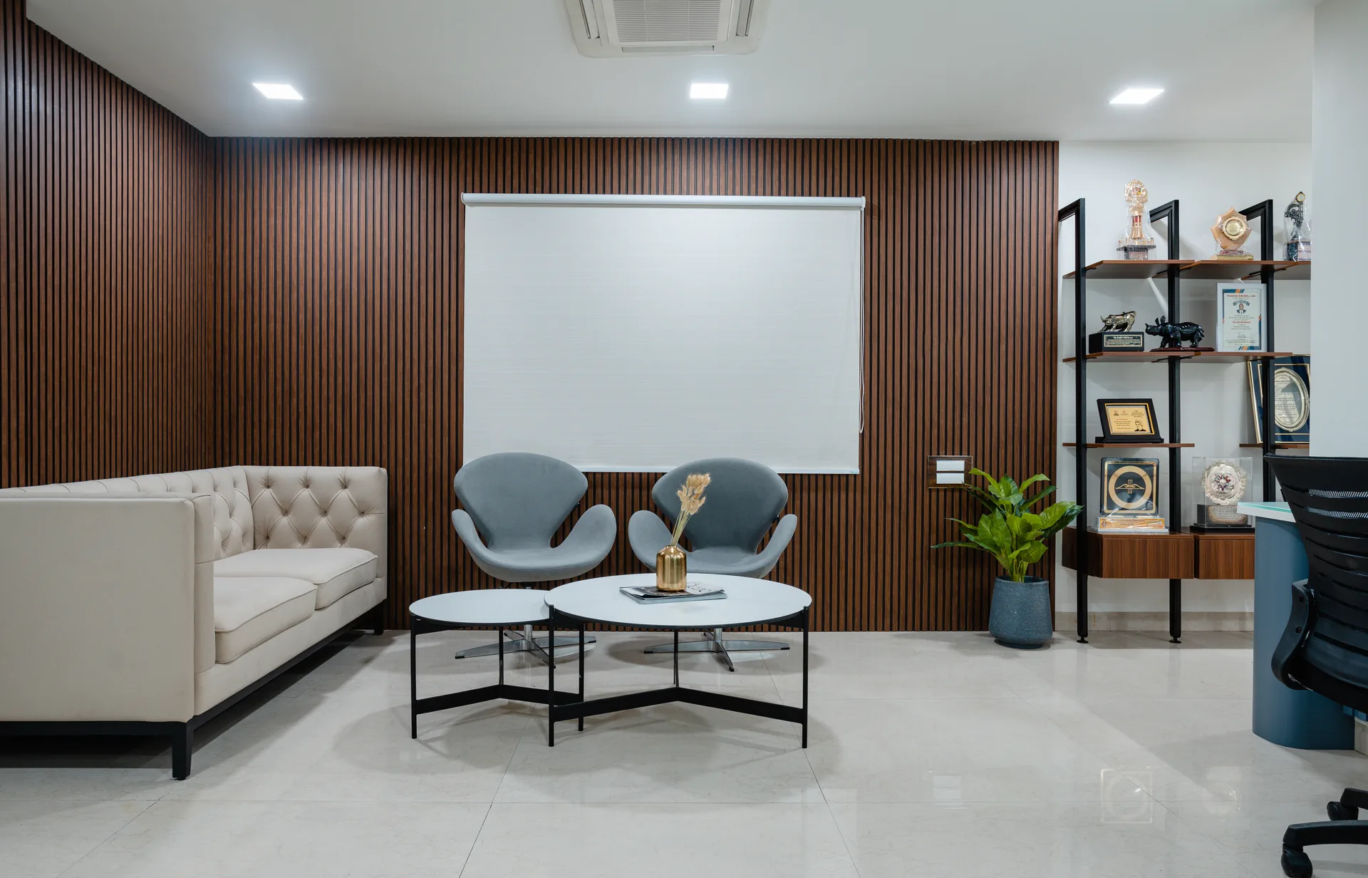 A contemporary executive cabin blending warm wooden textures, glass partitions, elegant seating, and streamlined workspaces to create a sophisticated, open, and welcoming professional environment.