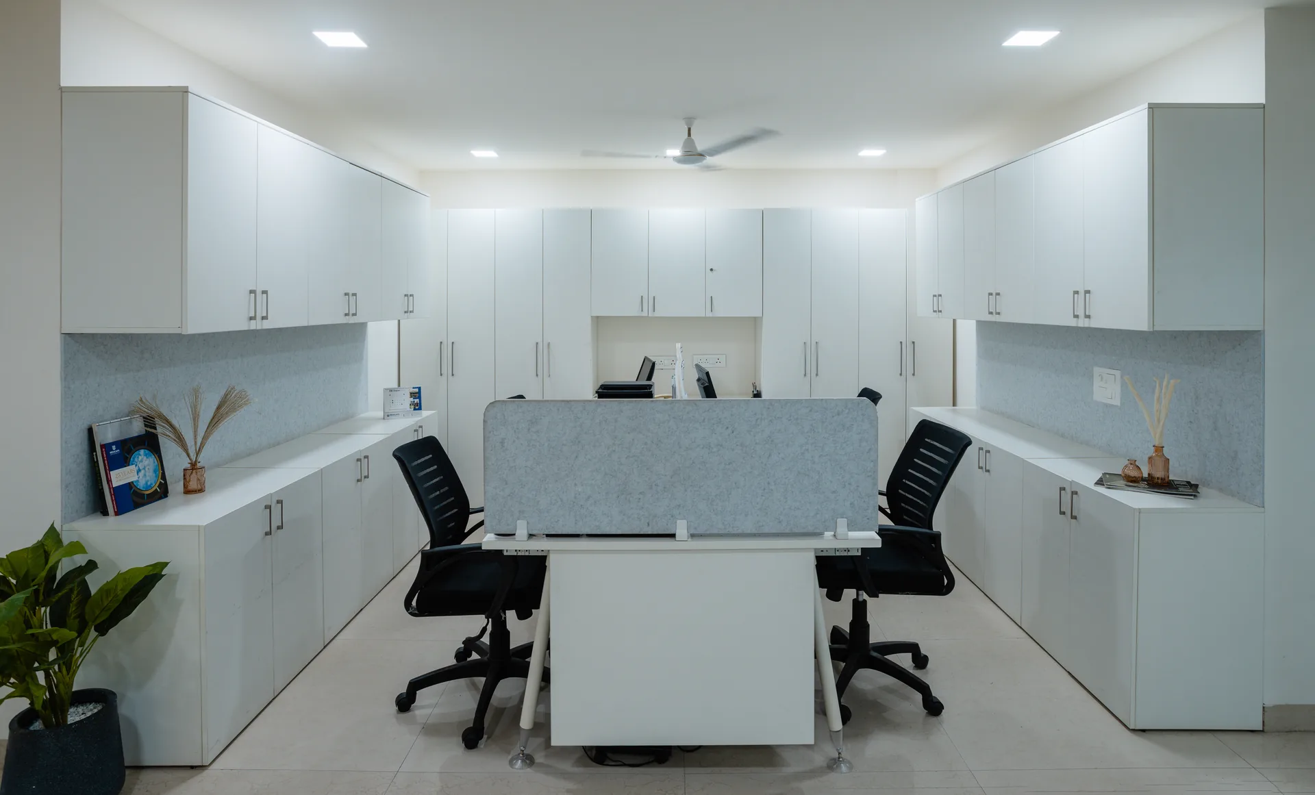 A bright and efficient workstation designed with streamlined desks, ample integrated storage, glass partitions, and a clean neutral palette for a focused and collaborative workspace.