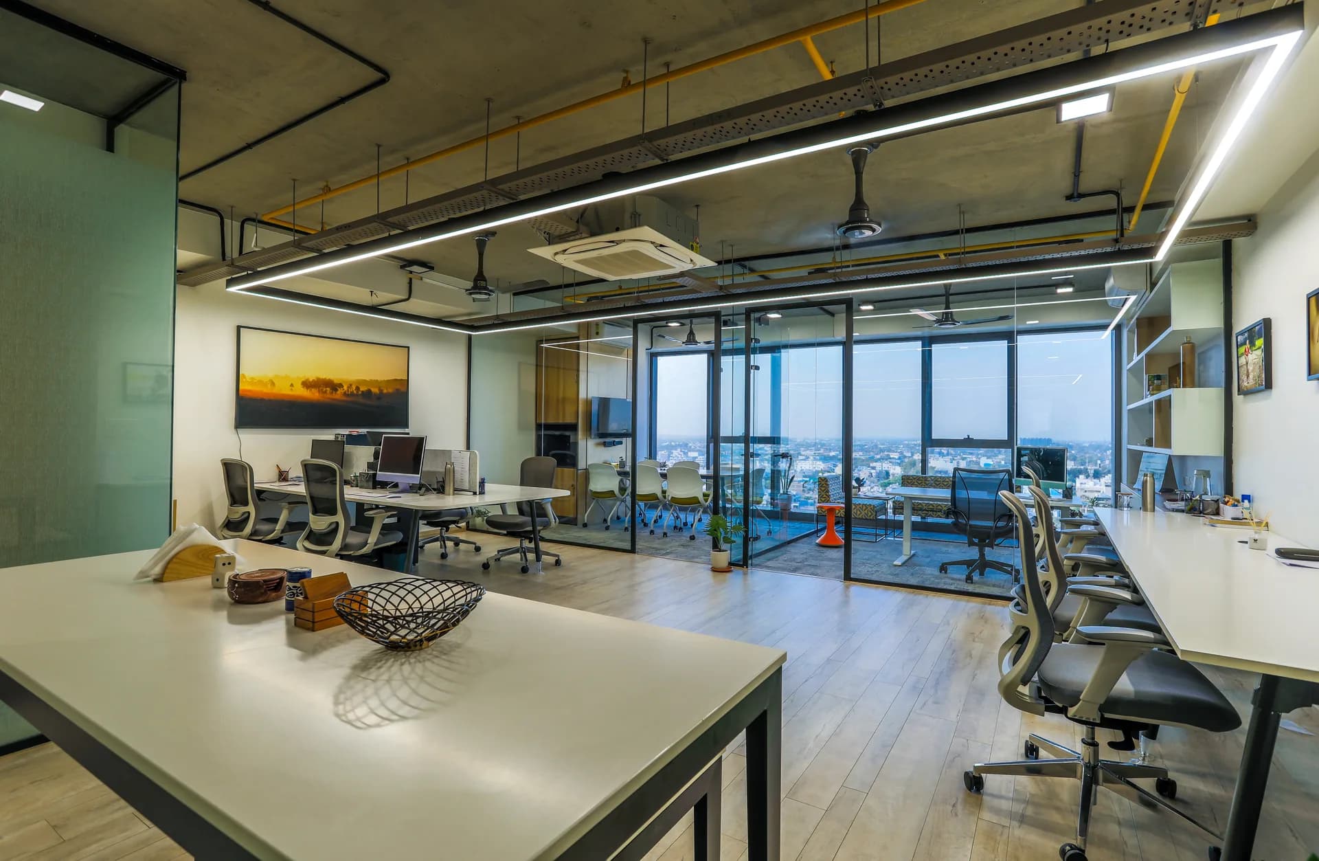A collaborative open workspace featuring exposed ceilings, glass partitions, ergonomic workstations, and abundant natural light, creating a spacious, energetic environment designed for productive teamwork.