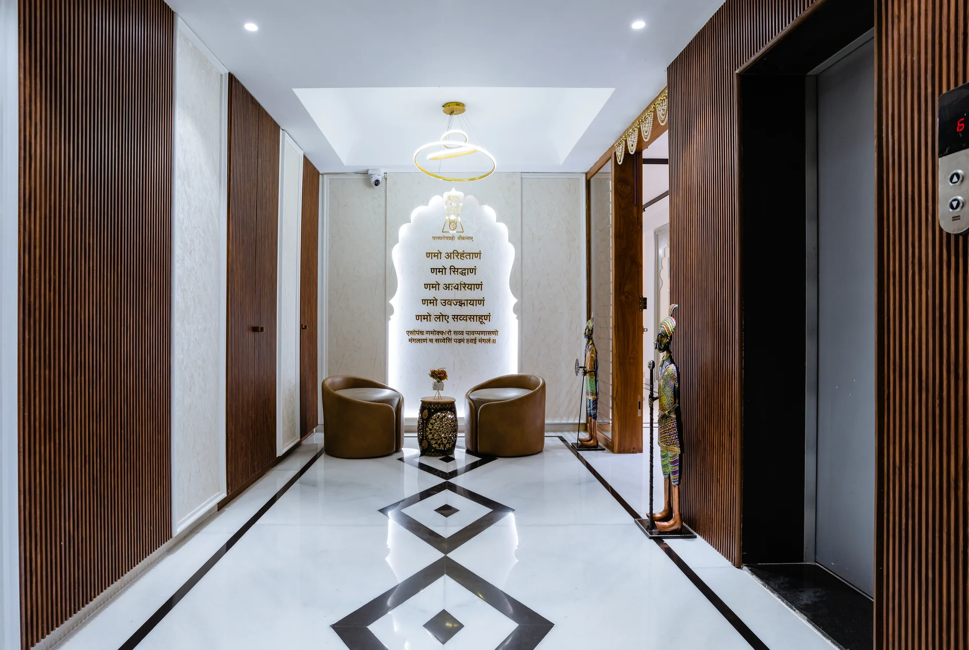A serene foyer featuring warm wooden accents, elegant lighting, refined seating, and a beautifully illuminated spiritual feature wall, creating a welcoming entrance rooted in tradition.