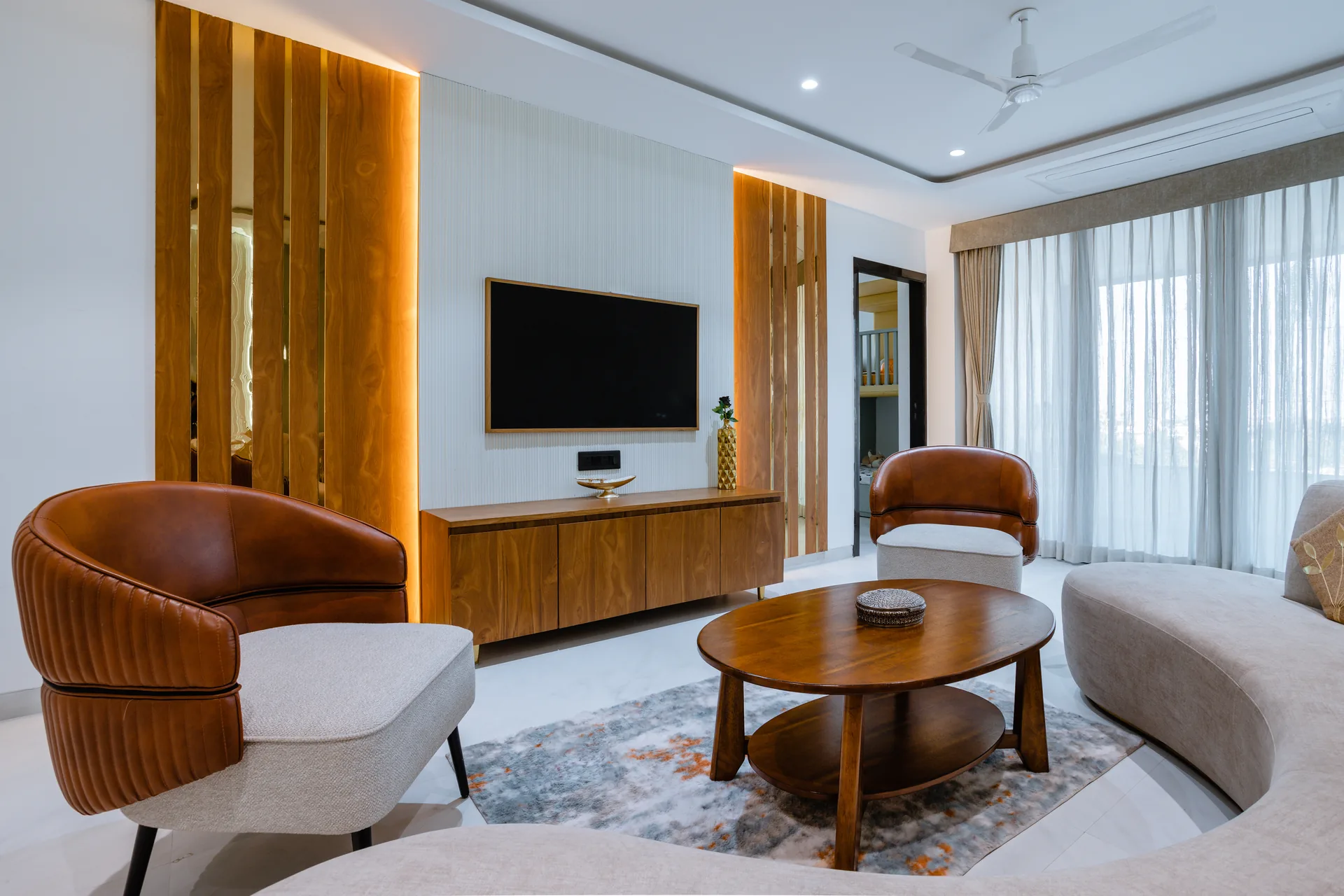 A refined living room featuring warm wooden accents, sculptural furniture, subtle traditional detailing, and layered lighting, creating an elegant balance of contemporary comfort and timeless character.