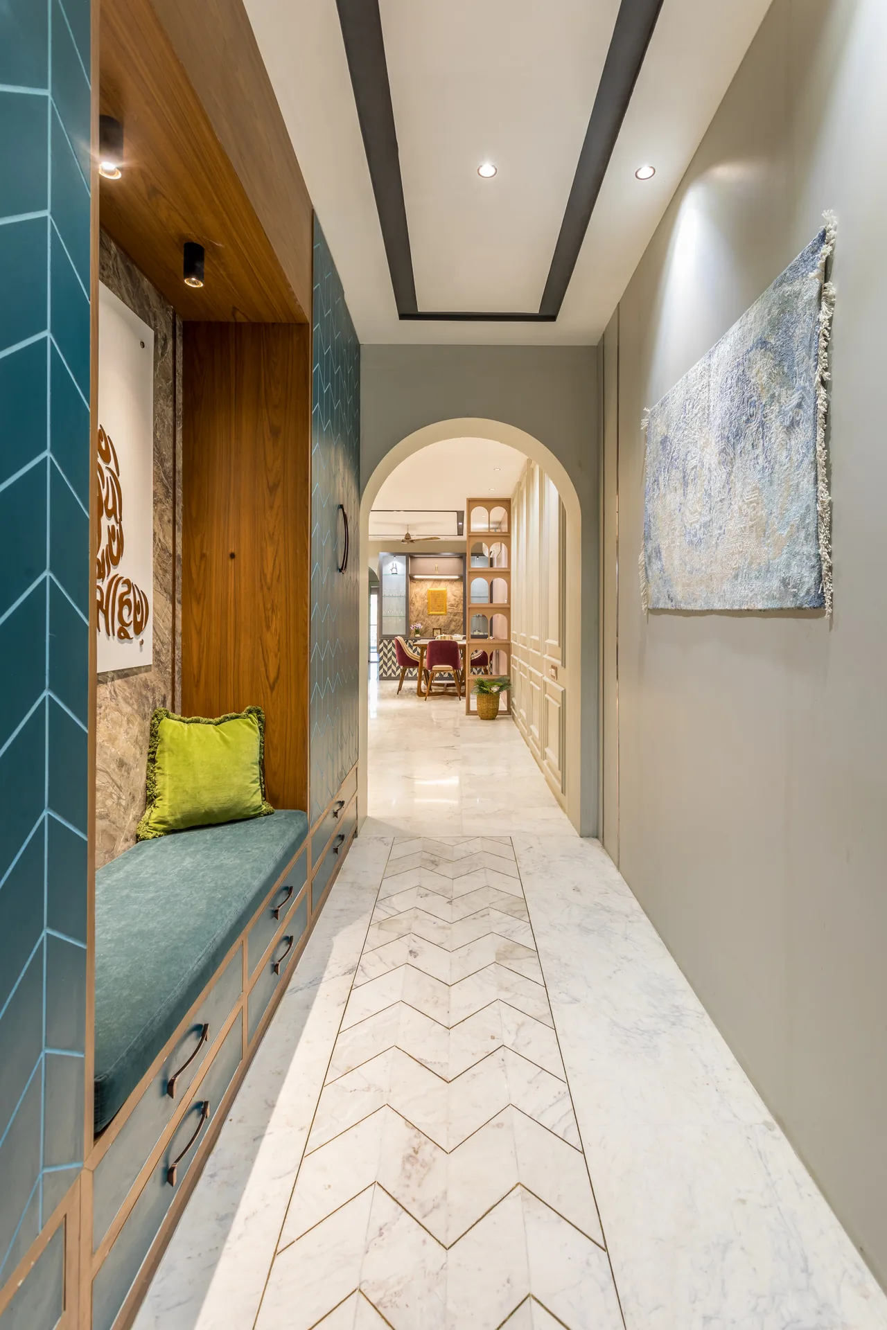 A distinctive entry foyer featuring warm wooden paneling, bold blue accents, geometric patterns, and curated artwork, creating a welcoming transition with contemporary character and warmth.