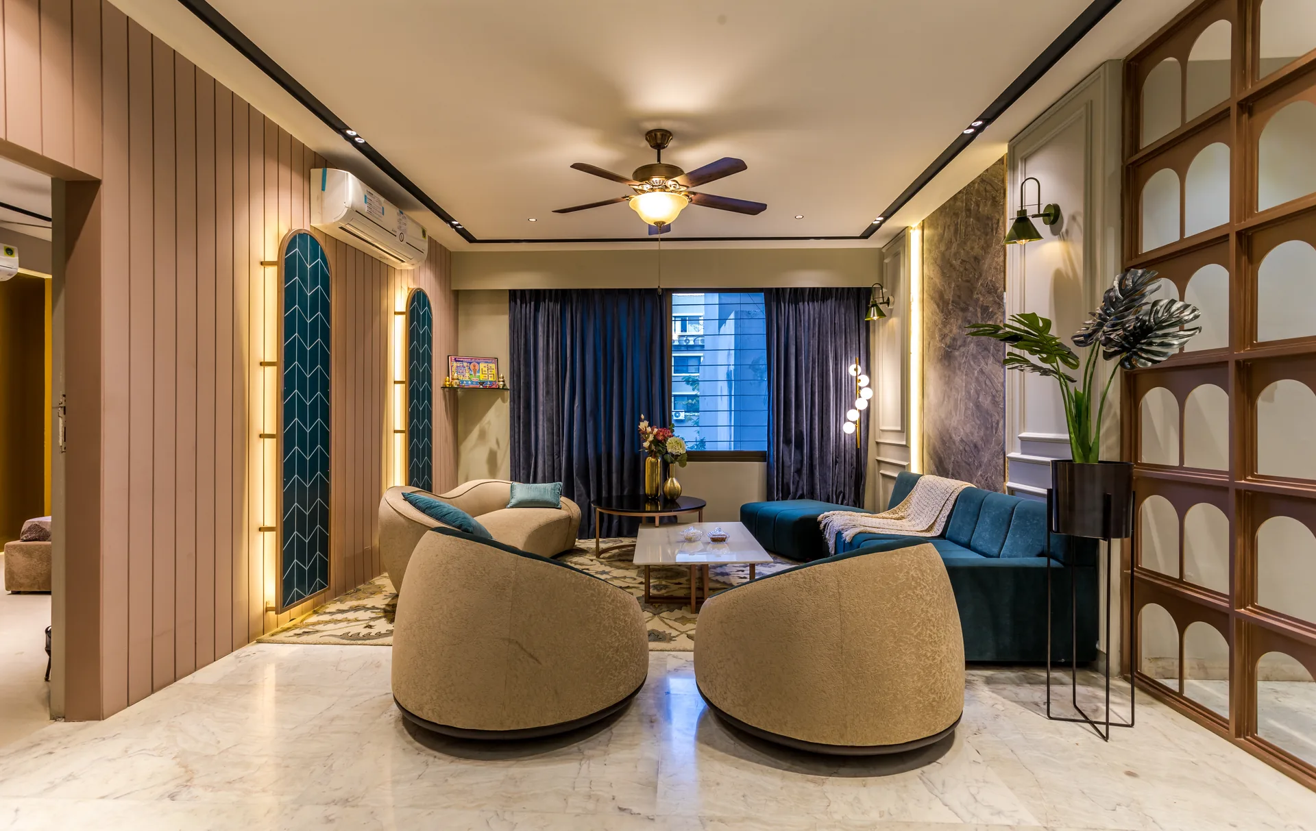 A warm and inviting living room featuring curved furniture, teal accents, layered wall detailing, ambient lighting, and curated décor, creating a sophisticated yet comfortable family space.